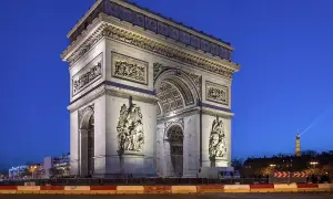 Majestatyczny łuk triumfalny w Paryżu, oświetlony nocą, z wieżą Eiffla w tle.