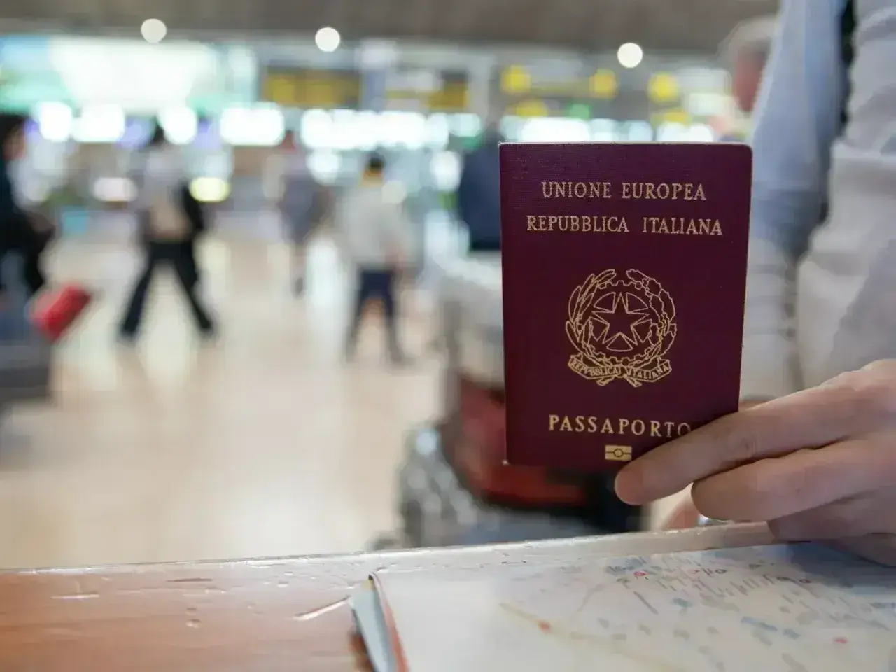 Włoski paszport w dłoni, w tle lotnisko. Czy do Serbii potrzebny jest paszport? Sprawdźmy!