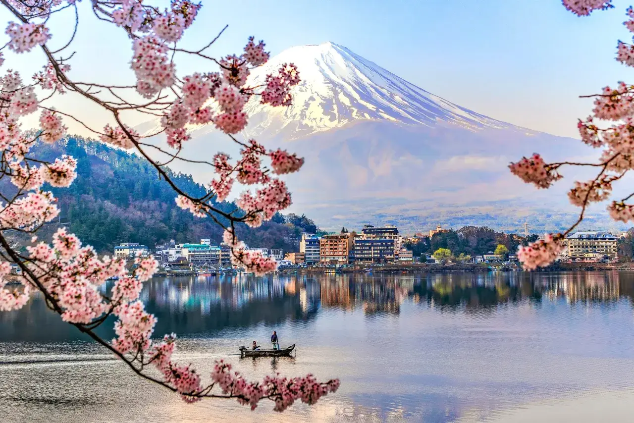 Wiosna na wyspach Japonii: kwitnące wiśnie, spokojne jezioro z łodzią i majestatyczny Fudżi.