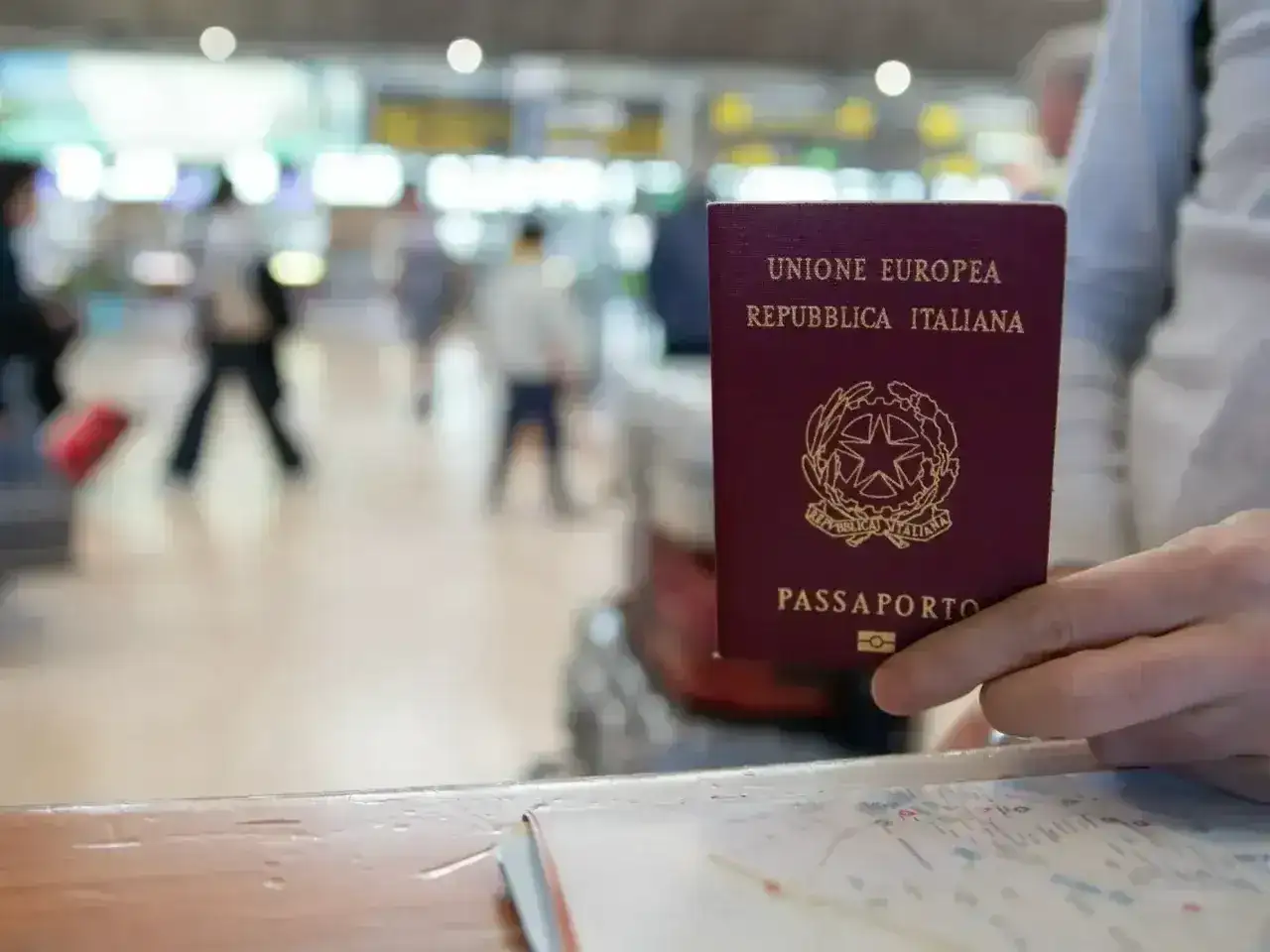 Włoski paszport w dłoni, w tle lotnisko. Czy do Serbii potrzebny jest paszport? Sprawdźmy!