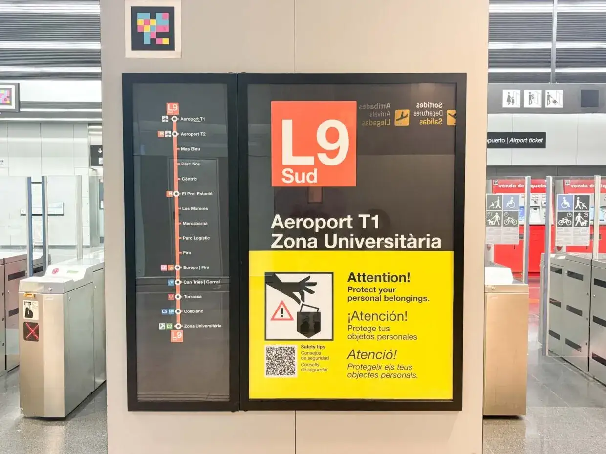 Tablica informacyjna na barcelona lotnisko z linią metra L9 Sud, wskazująca drogę do Aeroportu T1 i innych stacji.