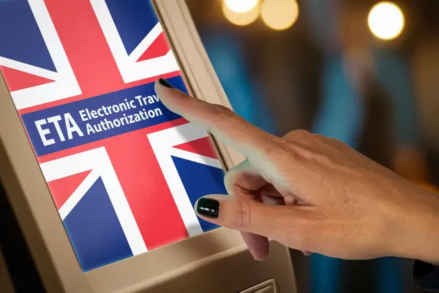 Dłoń dotyka ekranu z flagą Wielkiej Brytanii i napisem ETA Electronic Travel Authorization. To krok do uzyskania wizy do UK.