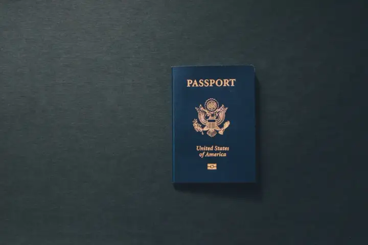 Niebieski paszport USA leży na ciemnym tle. Dokument przypomina o tym, ile ważny jest paszport dla podróżujących.